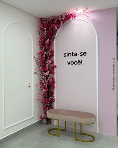 a bench sitting in front of a pink wall with flowers growing up it's side