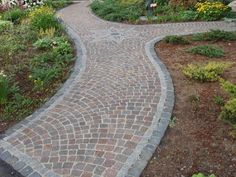 a brick walkway in the middle of a garden