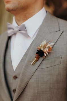 a man in a gray suit with a flower on his lapel and bow tie