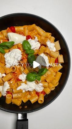 a skillet filled with pasta and cheese on top of a stove burner next to a white wall