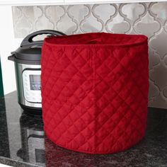 a red pot holder sitting on top of a counter next to an electric pressure cooker