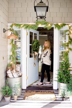 a woman standing in front of a door with christmas decorations on the outside and inside