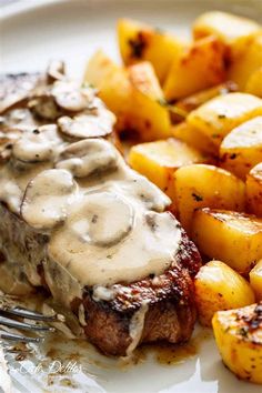 a white plate topped with meat covered in gravy and potatoes