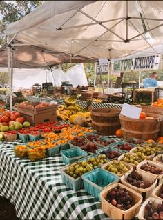 an outdoor farmers market with lots of fresh fruits and vegetables on tables under a tent