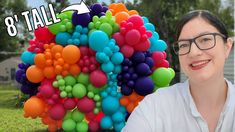 a woman with glasses is standing in front of a bunch of balloons that say 8 tall