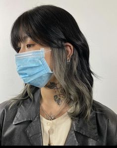 a woman wearing a blue face mask and black leather jacket with tattoos on her chest