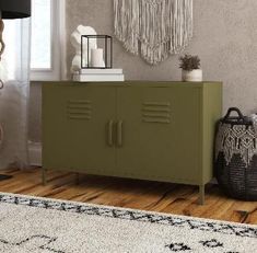 a green cabinet sitting on top of a wooden floor next to a lamp and rug