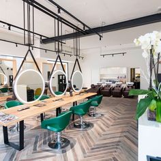 a long table with green chairs and mirrors on the wall in a room that has wood flooring