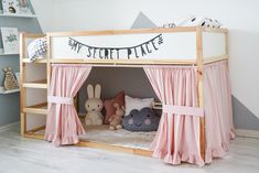 a child's bed with pink curtains and stuffed animals on the bottom bunk beds