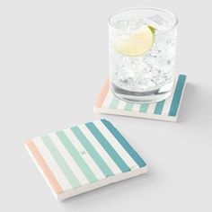 two coasters with different colored stripes and a lemon slice on one side, sitting next to each other