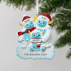 an ornament hanging from a christmas tree with two blue monsters on it's back