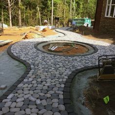 an outdoor fire pit surrounded by rocks and gravel in the middle of a yard area