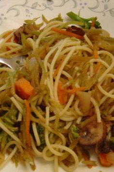 a white plate topped with pasta and veggies next to a fork on top of a table