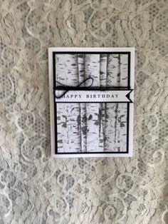 a birthday card hanging on the wall in front of a lace covered wallpaper with an arrow