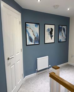 a room with blue walls and pictures hanging on the wall, along with white stairs