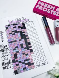 the contents of a planner, lipstick, and pen on a white table with flowers