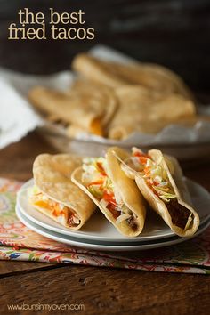 three tacos on a plate next to some pita bread