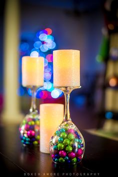 three candles sitting on top of a table next to a glass vase filled with beads