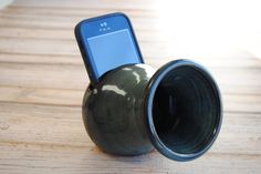 a cell phone in a vase sitting on a wooden table with it's lid open