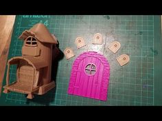 there is a small pink house next to a paper cutout that looks like a fairy door