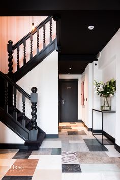 a black and white checkered floor next to a stair case with a plant on it