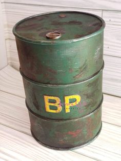 two green barrels sitting on top of a wooden floor next to a white wall with yellow lettering