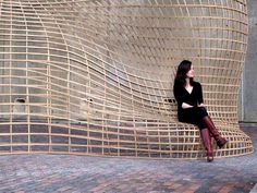 a woman sitting on top of a wooden chair in front of a wall and floor