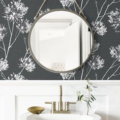 a white sink sitting under a round mirror next to a wall mounted faucet