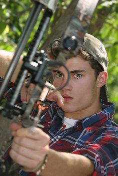 a young man holding a bow and aiming it at something