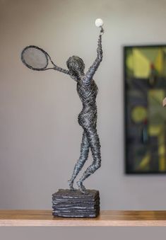 a sculpture of a person holding a tennis racquet on top of a wooden table