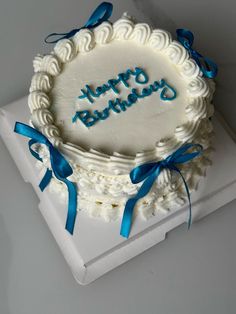 a white cake with blue ribbon and happy birthday written on it