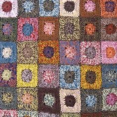 a multicolored patchwork quilt with square and flower designs on the center, in various colors