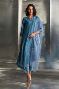 In a standout blue steel hue, this chanderi asymmetrical kurta set features feather-touch pure organza patchwork with intricate golden nakshi hand embroidery and a delicate scalloped border. Complete the look with a dreamy pure organza dupatta showcasing nakshi handwork and scalloped-edge narrow bottoms. The bottom is elasticated with a drawstring for added comfort. Blue Slub Silk Kurta With Sheer Dupatta, Blue Kurta With Sheer Dupatta In Raw Silk, Blue Raw Silk Kurta With Sheer Dupatta, Blue Organza Kurta For Diwali, Blue Organza Kurta With Sheer Dupatta, Blue Organza Dupatta With Gota Work, Feather Touch, Scalloped Border, Organza Dupatta