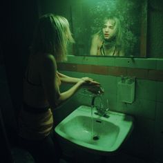 a woman is standing in front of a mirror and looking at herself in the bathroom