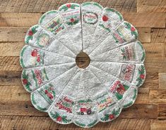 a paper doily is sitting on a wooden surface with christmas decorations around it and the words merry written in red, white and green