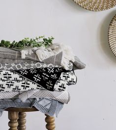 a pile of blankets sitting on top of a wooden stool next to a wall mounted planter