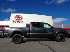 a gray truck parked in front of a toyota dealership