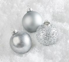 three silver and silver christmas ornaments on snow