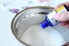 a hand is holding an empty bottle in a metal container filled with water and sugar