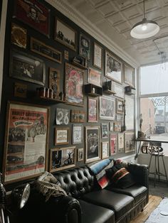 a living room filled with furniture and lots of framed pictures on the wall above it