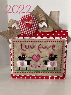 a red and white cross stitched bag with two sheep on it's side