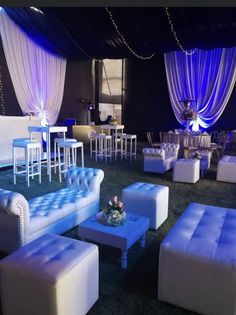 a room filled with white couches and tables covered in blue draping on the ceiling