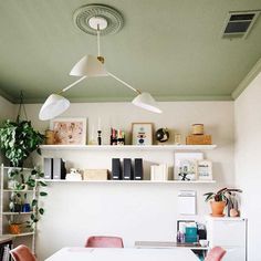 a white table and some pink chairs in a room with shelves on the wall behind it