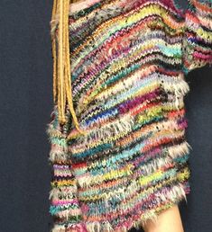 a multicolored sweater with fringes hanging from it's back and side