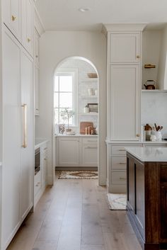 the kitchen is clean and ready for us to use it's white cabinets, wood floors, and marble counter tops