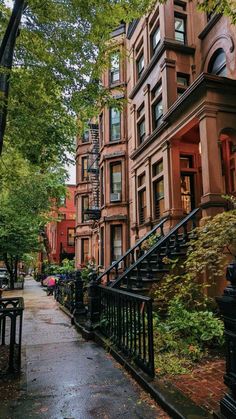 an alleyway with many brownstone buildings and wrought iron railings in the rain