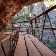 a wooden bench sitting under a cliff next to a tree filled mountain side with lots of trees