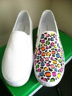 pair of white shoes with multicolored dots on them sitting on top of a green box