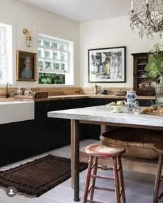 a kitchen with black cabinets and white countertops has a marble top island in the center