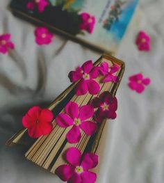 an open book with pink flowers on it sitting on top of a white bed sheet